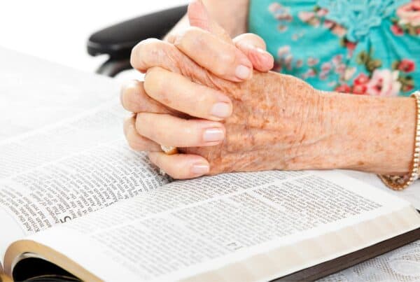 Elderly hands clasped over an open book, highlighting senior-friendly gifts for dads on Father’s Day.