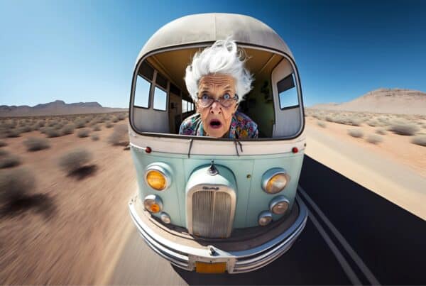 Elderly woman with gray hair surprised in a vintage camper van in desert landscape.