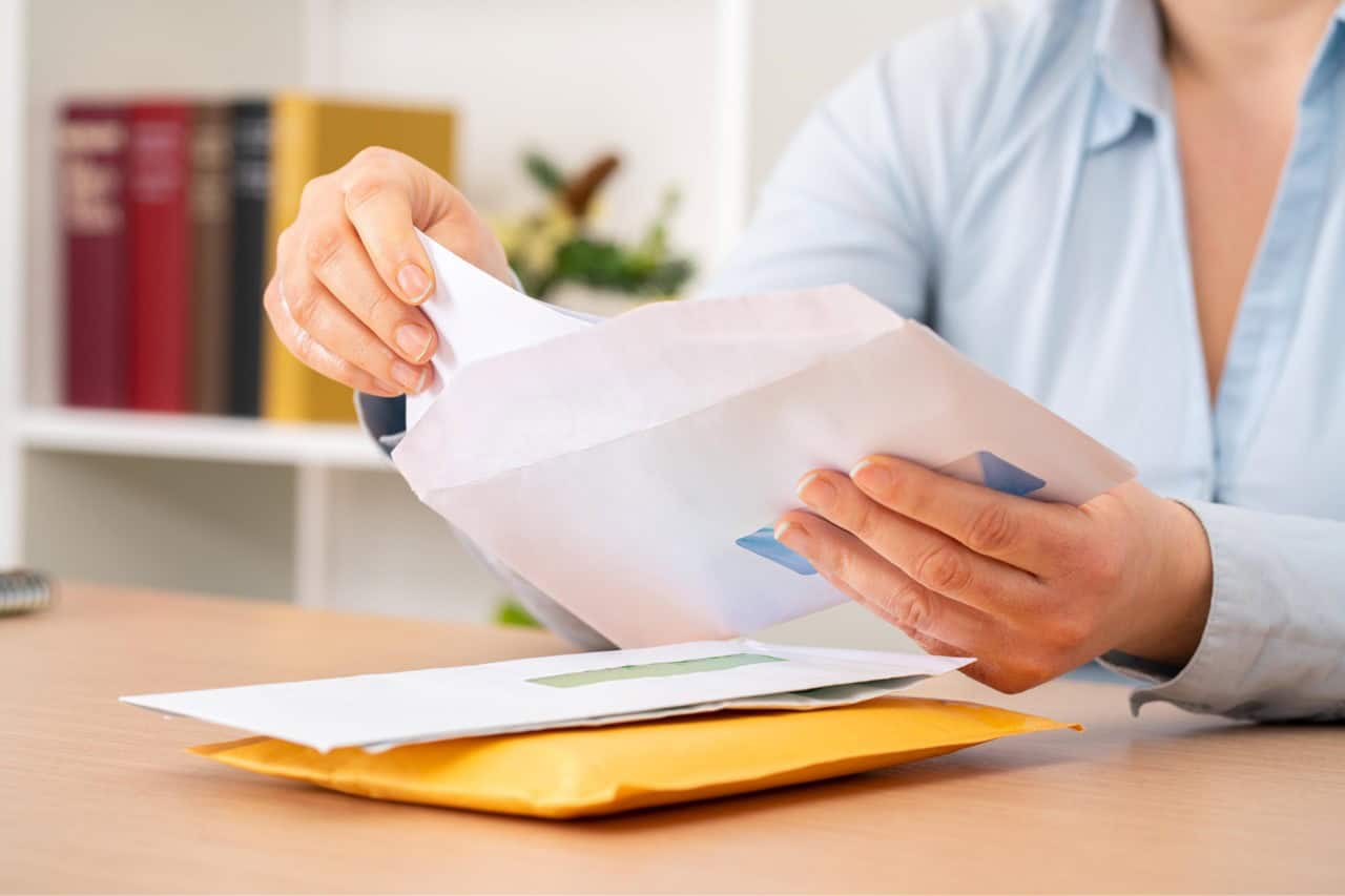 Woman handling mail with gray hair, promoting confidence in natural hair.