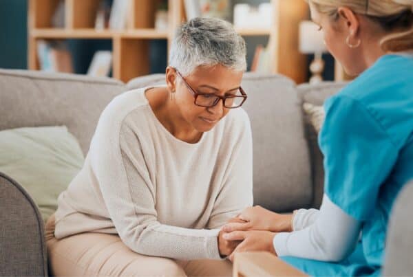 Elderly woman receiving emotional support from caregiver at home.