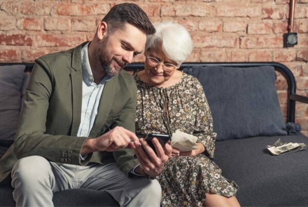 Older woman with gray hair and a man looking at a phone together.