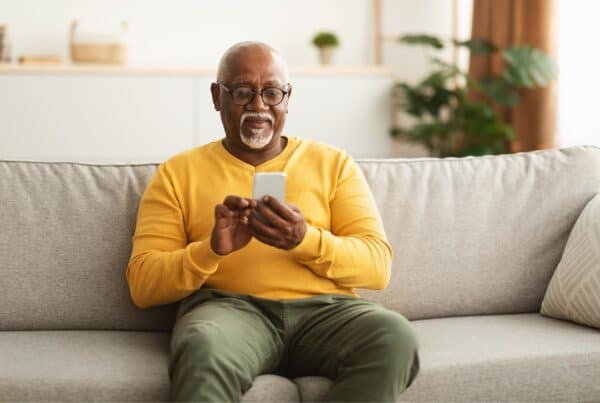 Elderly man with gray hair using smartphone at home.