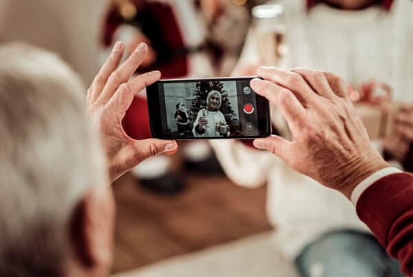 Older woman taking a photo with her smartphone at a social gathering.