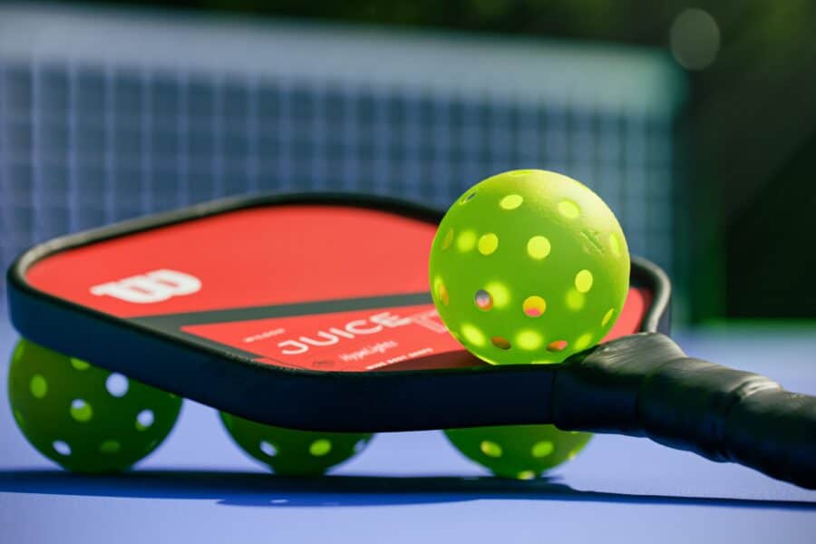 Pickleball paddle and balls on a court, perfect for senior players.