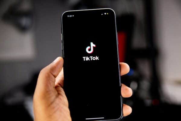 Close-up of a hand holding a smartphone displaying the TikTok app logo.