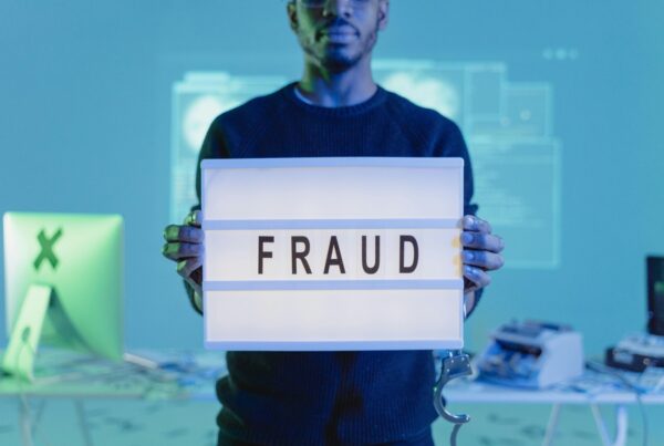 Person holding a sign that says "FRAUD" highlighting elder fraud awareness.